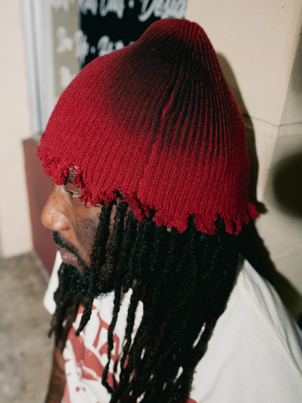 Full side profile of the vintage-red distressed knit beanie with frayed edge